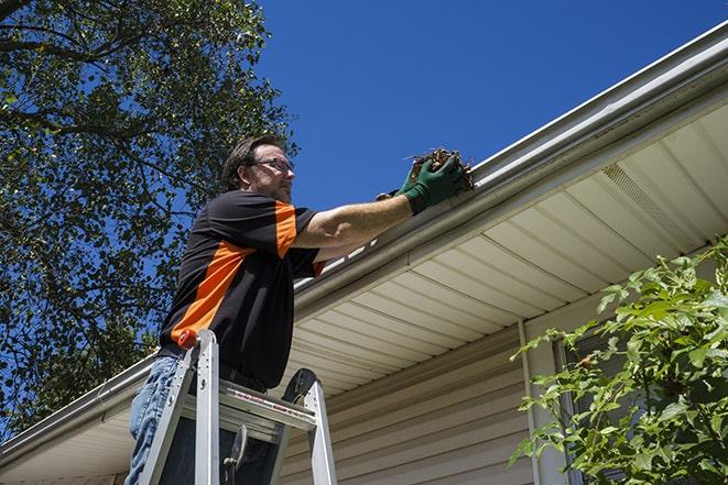 a skilled worker fixing broken gutter on a roof in Buena, WA